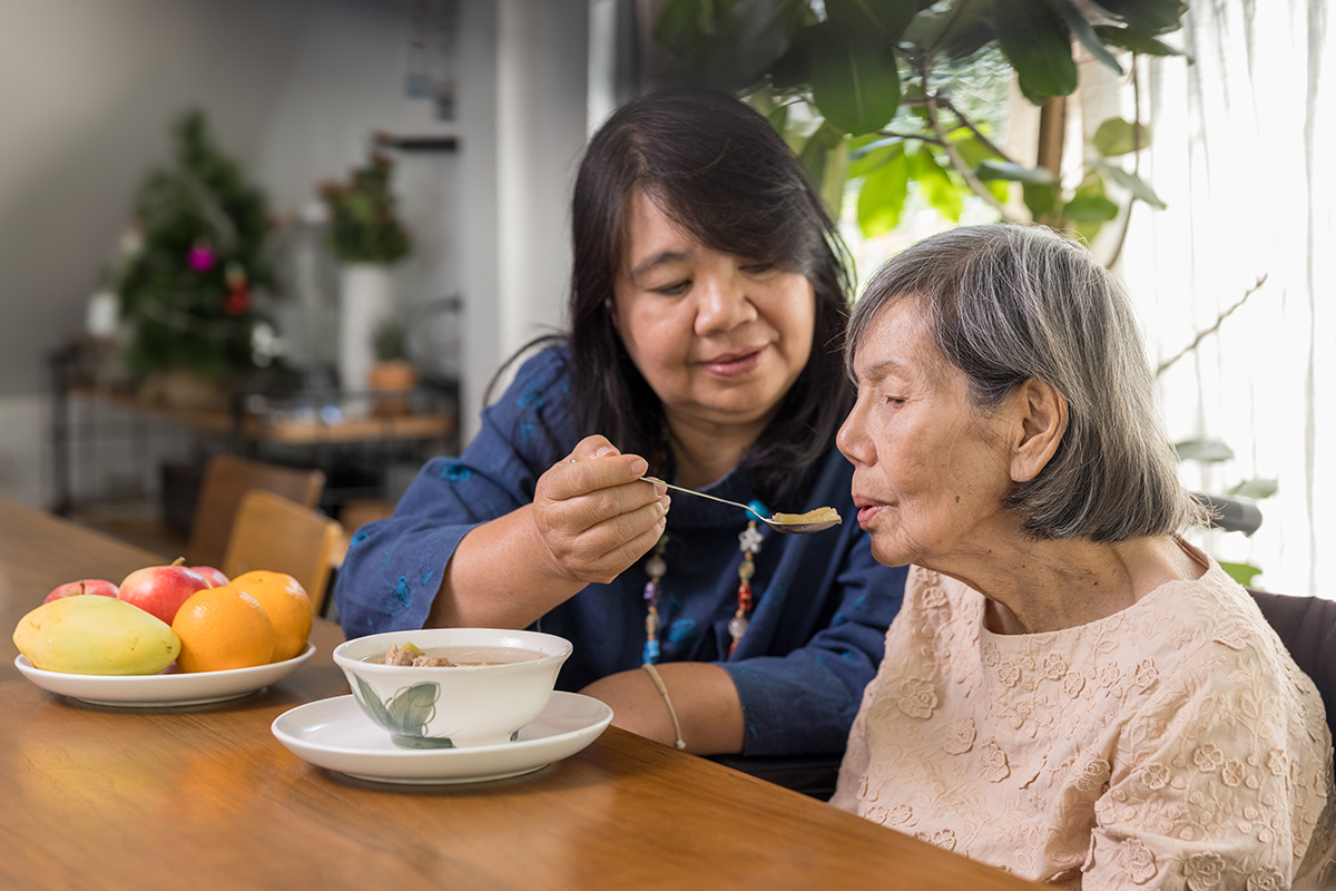 Woman feeding an older woman soup